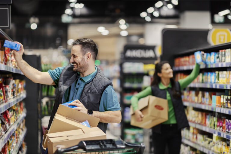 the employees putting groceries on aisle and exposing them at supermarket.